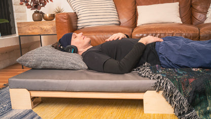 A person lying on a Crescendo Bass Bed while listening with headphones.