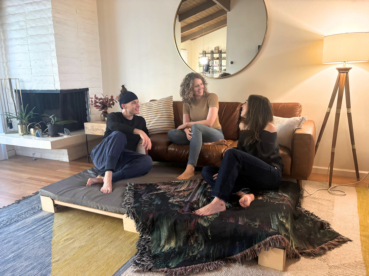 three people socializing in a living room with a Crescendo Bass Bed.