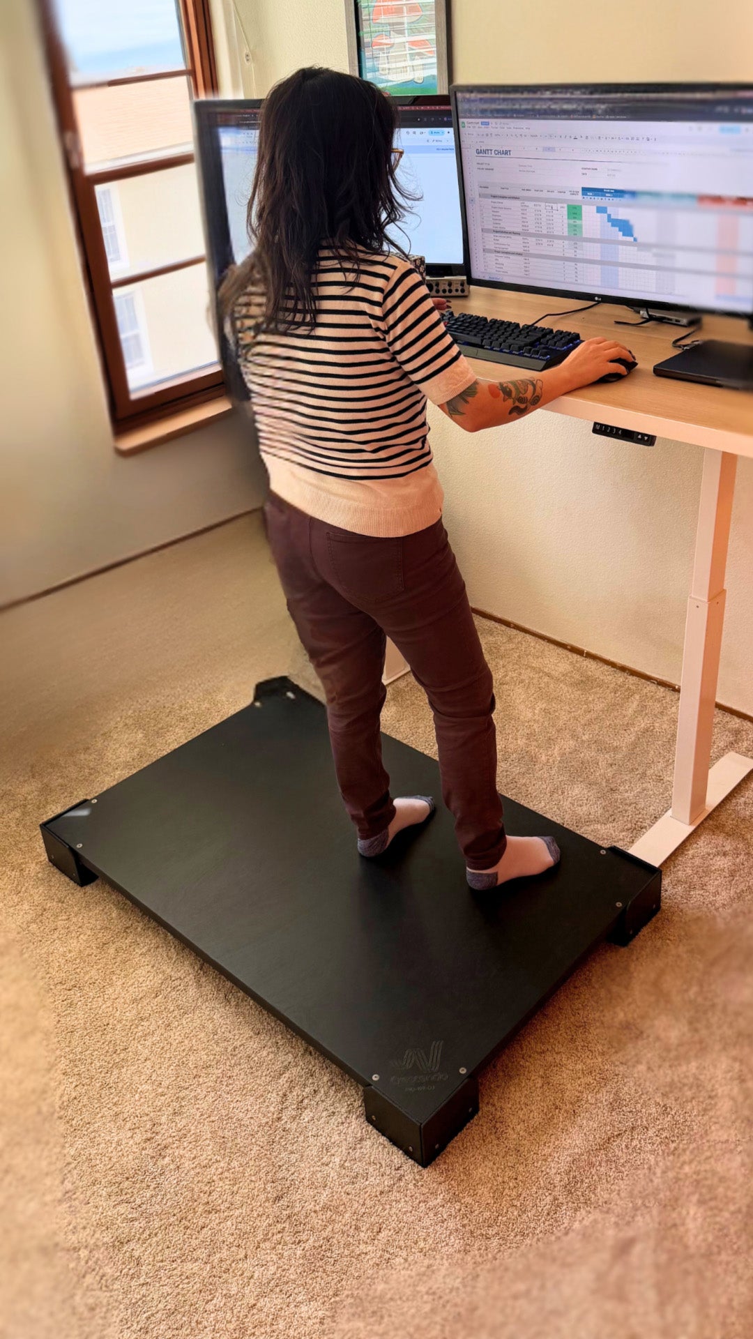 A Crescendo Studio Tile being used by a woman at a standing desk.