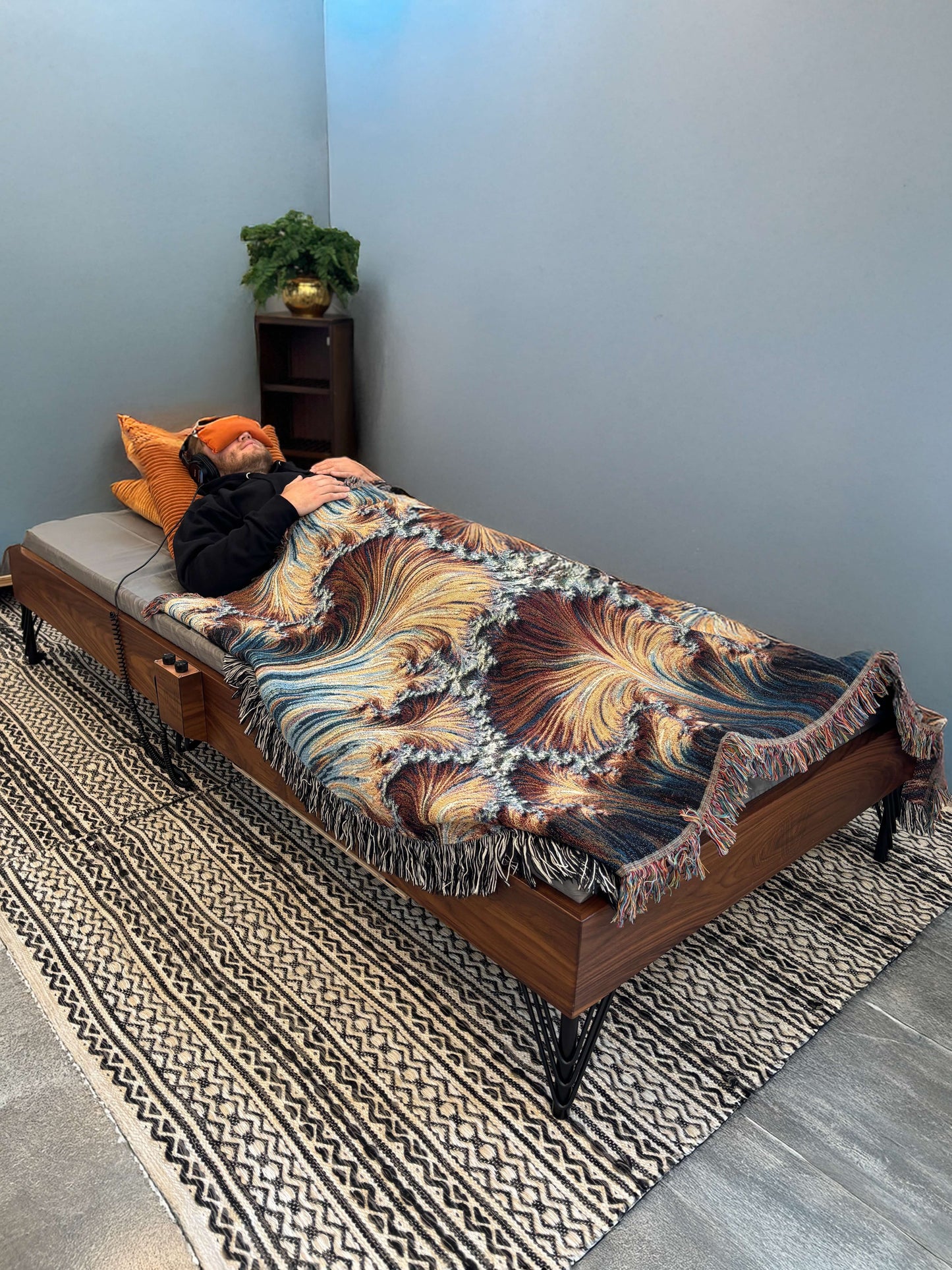 A walnut hardwood Crescendo Daybed with a listener in a room.